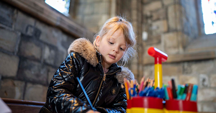 young girl drawing during arts and crafts session at Durham Cathedral.